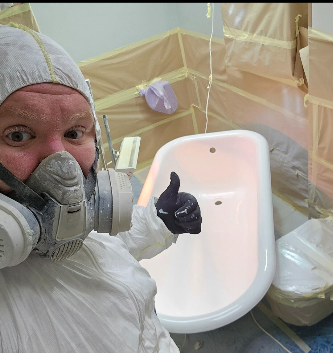photo of glossy baths owner photo of glossy baths re-enamelling owner Seamus with a thumbs up, in ppe, in a room full of masking up and a completed bath in Wolverhampton